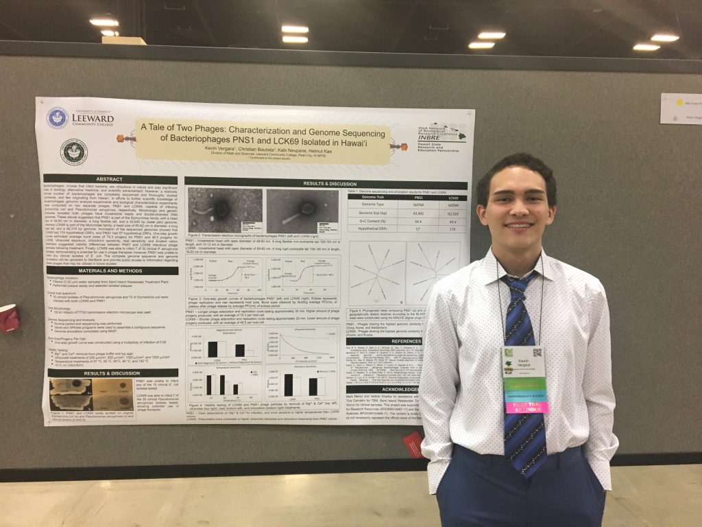 A picture of Kevin standing in front of his poster at SACNAS 2018.